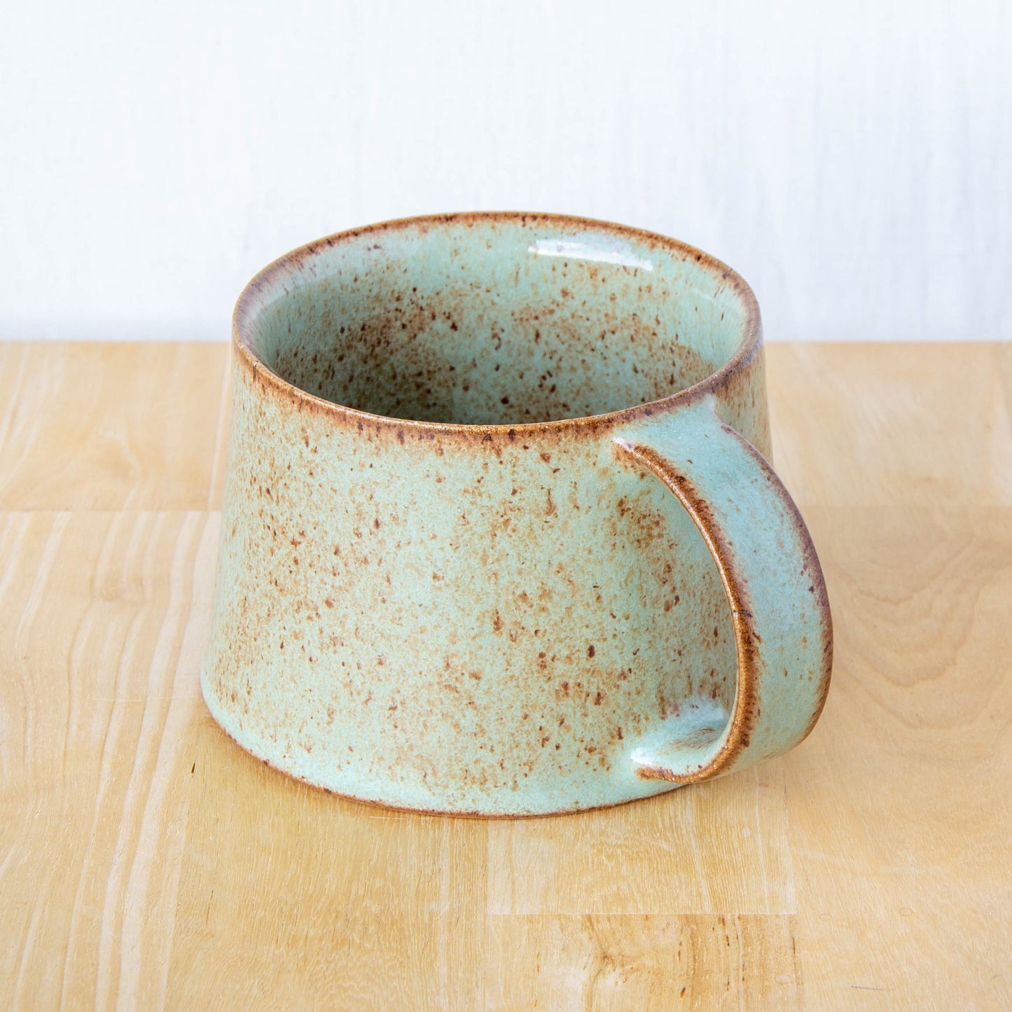 Handmade mug by Land and Line Ceramics New Zealand made pottery green mug tapered mug with rustic wabi-sabi style glaze