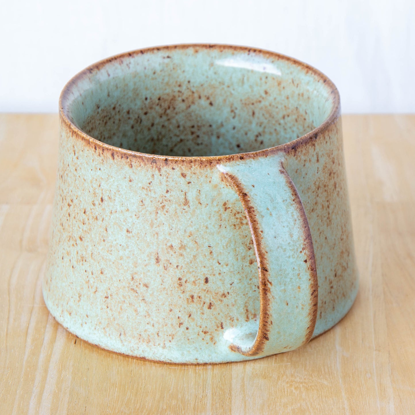 Handmade mug by Land and Line Ceramics New Zealand made pottery green mug tapered mug with rustic wabi-sabi style glaze