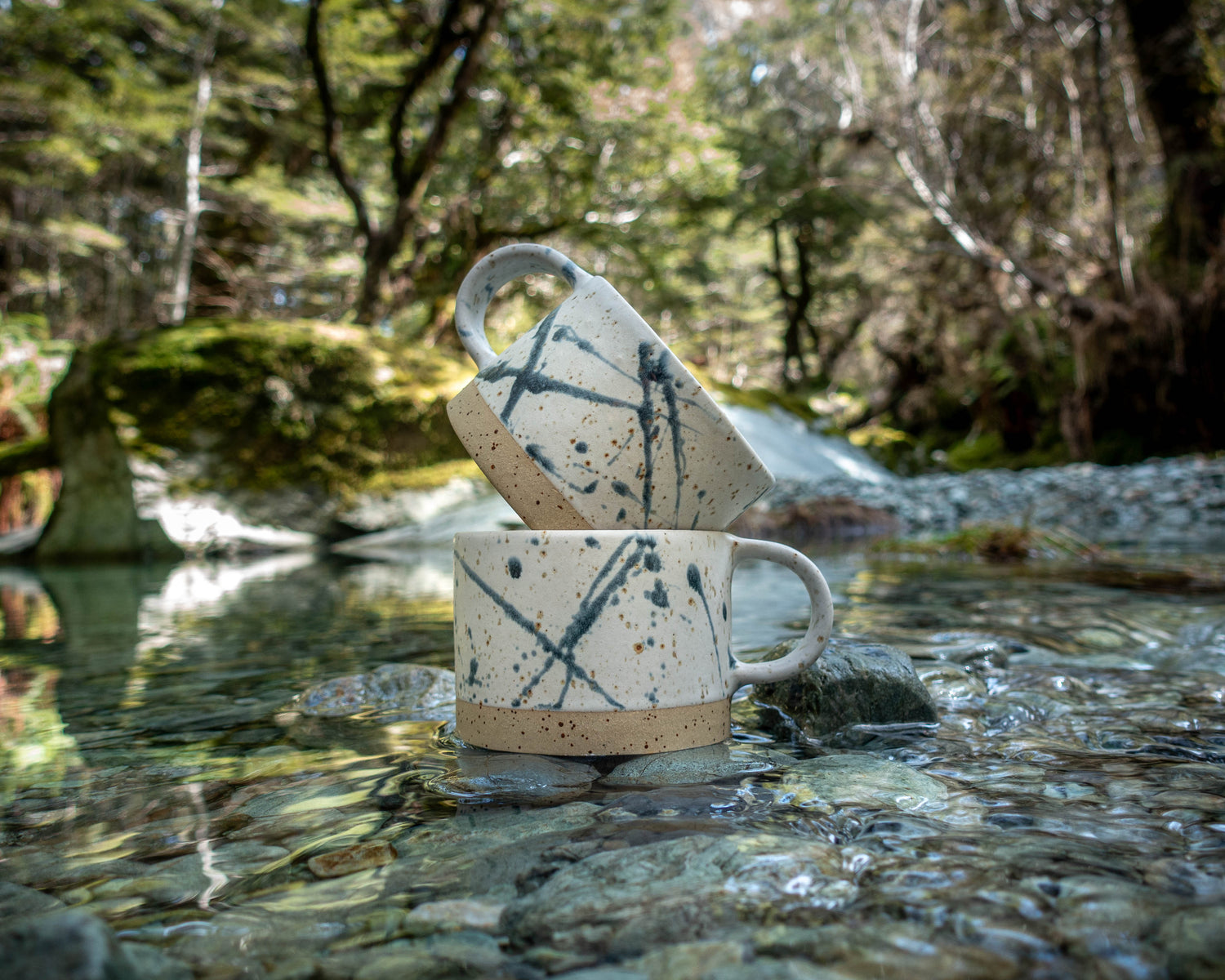 handmade coffee mug with abstract splatter pattern in a mountain stream made by land and line ceramics