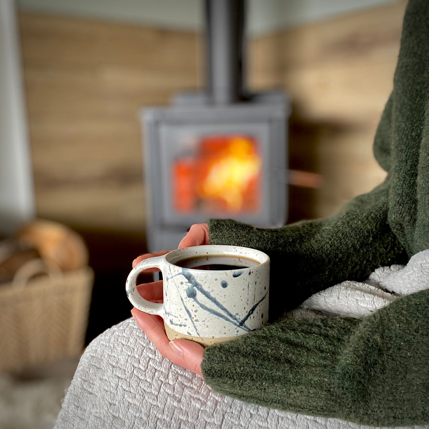 cozy scene with handmade coffee mug and chunky sweater next to fireplace New Zealand made pottery by Land and Line Ceramics